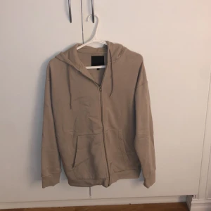 Beige hoodie från 157 - Säljer en beige/ ljusbrun hoodie från 157 i storlek S. Den har en dragkedja framtill och en mysig huva. Perfekt för kyliga dagar. Hör av dig vid intresse!