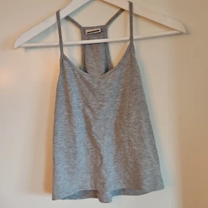 Grå linnetopp - Säljer en stilren grå linnetopp med smala axelband och en lös passform. Perfekt för varma dagar eller som ett lager under en jacka. Toppen har en enkel design som gör den lätt att matcha med olika outfits.