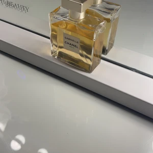 Gabrielle Chanel Parfym - Elegant parfym från Chanel i en stilren, fyrkantig glasflaska med en gyllene vätska. Flaskan har en silverfärgad kork med Chanels ikoniska logotyp. Perfekt för den som älskar lyx och tidlös design. Andvänt lite men ny pris 1500 