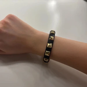 Svart armband med nitar💕 - Snyggt svart armband med guldnitar som ger en tuff och stilren look🥰💕den är aldrig använd så den är i nyskick och det är en jättefin liknande version av valentino💓