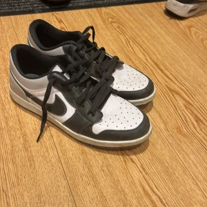 Nike Air Jordans i svart och vit - Säljer ett par klassiska Nike Air Jordans i svart och vit. Skorna har en stilren design med snörning och perforerade detaljer på ovansidan för bättre ventilation. Perfekta för både vardag och sportiga aktiviteter.