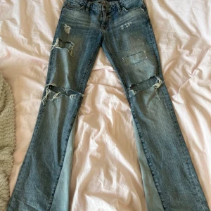 Blå slitna jeans med bootcut  - Säljer ett par blå crocker jeans med bootcut och slitna detaljer. Jeansen har en klassisk femficksdesign och en bekväm passform. Perfekta för en avslappnad stil. Har sytt om de till bootcut. Säljer endast vid bra bud! Skriv om ni har några frågor! 💞