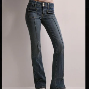 Blå bootcut jeans - Snygga blå bootcut jeans med låg midja och klassisk femficksdesign. Jeansen har en stilren look med framträdande sömmar och en knappgylf. Perfekta för en avslappnad stil. Dom är storlek 40 men passar mig som har 38🤩nypris 700