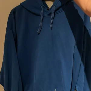 Blå hoodie - Säljer en snygg blå hoodie med justerbar dragsko i huvan. Perfekt för en avslappnad stil och passar bra till jeans eller joggers. Hör av dig vid intresse!