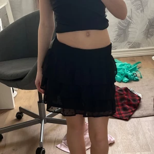 Svart volangkjol - Snygg svart kortkjol med flera lager volanger. Kjolen har en jätte elastisk midja för bekväm passform och ett tyg prickigt mönster. Perfekt för en sommar dag! Använd runt 5 gånger men den är som ny. Kostade 300 kr när jag köpte den. Super skön och jätte söt! 😍