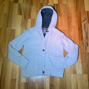 Vit fodrad cardigan / S - Säljer en vit cardigan/jacka med knappar och fodring/ päls. Cardiganen har ett snyggt kabelstickat mönster och praktiska fickor framtill. Perfekt för kyliga dagar! Storlek S, vit. Kom gärna med bud