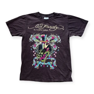 Vintage Ed Hardy brun  t-shirt med drakmotiv - Cool brun t-shirt från Ed Hardy med ett färgglatt drakmotiv på framsidan. T-shirten är gjord i bomull och är i fint skick. Storlek M men passar mer som S.