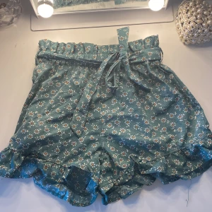 Blommiga gröna shorts från Shein - Snygga gröna shorts från Shein med ett blommigt mönster och volang. Storlek 11/12 år. 