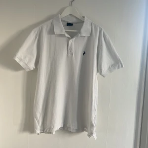 Vit pikétröja från Peak Performance - Säljer en stilren vit pikétröja från Peak Performance. Tröjan har en klassisk krage med knappar och en liten logotyp på bröstet. Perfekt för en avslappnad och sportig look.