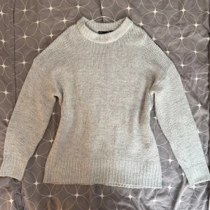 Grå stickad tröja - Säljer en stilren grå stickad tröja med rund hals och långa ärmar. Tröjan har en ribbad struktur vid ärmslut och nederkant. Strlk M, passar XS-M