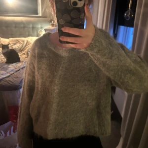 Grå fluffig tröja  - Säljer en supermjuk och fluffig grå tröja. Den har en avslappnad passform med långa ärmar och en rund halsringning. Perfekt för kyliga dagar när du vill känna dig både bekväm och stilren. Tröjan är i nytt skick och har fortfarande etiketten kvar.