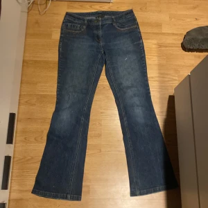 Blå bootcut jeans från INC International Concepts - Snygga blå bootcut jeans från INC International Concepts med broderade detaljer på bakfickorna. Tillverkade i en bomullsblandning med lite stretch för extra komfort. Perfekta för en avslappnad stil med en touch av elegans.
