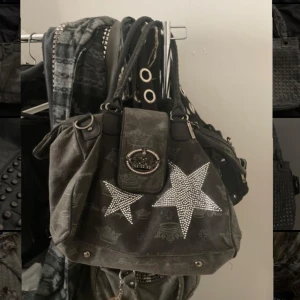 Svart axelväska med stjärndetaljer - Snygg svart axelväska med glittriga stjärnor och kronmönster. 