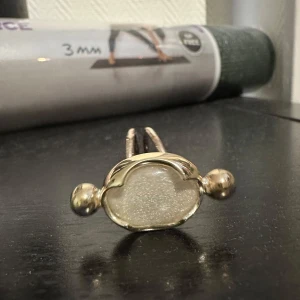 Silverpläterad ring med molnformad design - Elegant  ring med en unik molnformad design. Ringen har en glittrig yta i mitten och två små kulor på sidorna som ger en modern touch. Perfekt för att lägga till lite extra stil till din outfit.