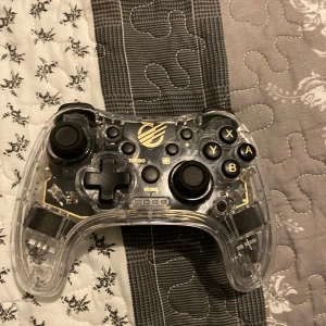 Genomskinlig spelkontroll med LED-belysning - Säljer en cool genomskinlig spelkontroll från KMD med inbyggd LED-belysning som lyser upp i grönt. Kontrollen har en klassisk layout med två analoga spakar, styrkors och knapparna A, B, X, Y. Perfekt för gamingkvällar med extra stil! 🎮✨