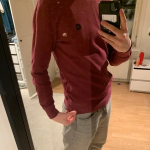 Vinröd tröja från J.Lindeberg - Säljer en stilren vinröd tröja från J.Lindeberg med U-ringning vid halsen och en diskret logga på bröstet. Tröjan är perfekt för en chill look och går alltid hem till outfitten.😉Den sitter rätt tajt på modellen - 183cm Nypris: 1399kr