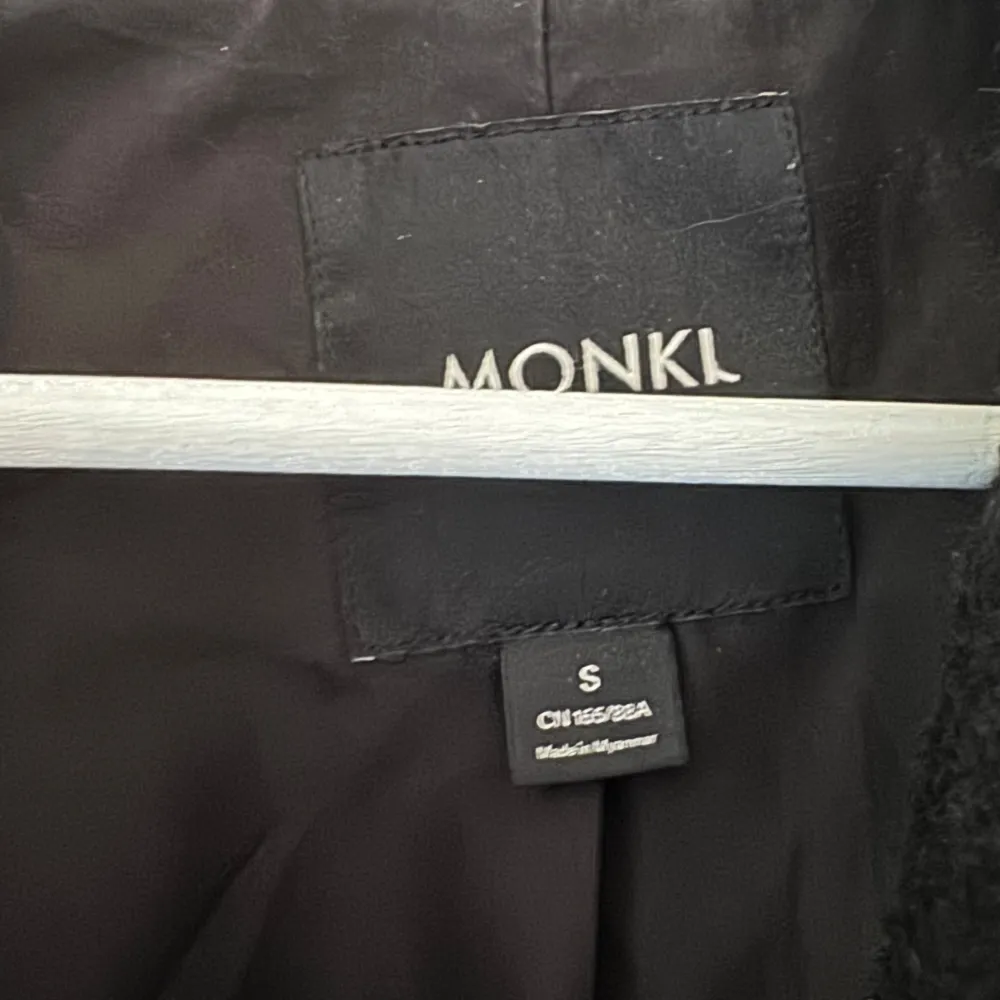 Snygg svart kappa från Monki i storlek S. Den har en klassisk design med knappar framtill och en stilren krage. Perfekt för kyligare dagar och ger en elegant touch till din outfit.. Takit.