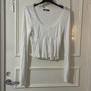 Vit långärmad topp  - Säljer en vit långärmad topp från Gina tricot. Toppen har en v-ringad design och en lätt croppad passform. Perfekt för lager-på-lager eller som den är. Tröjan är använd en gång men är som ny☺️