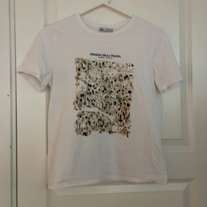 Vit t-shirt med leopardmönster - Säljer en vit t-shirt från Zara med ett coolt leopardmönster på framsidan. T-shirten har korta ärmar och en rund halsringning. Perfekt för en avslappnad stil.