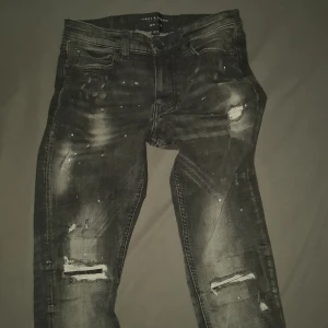 Svarta jeans från Supply & Demand - Coola svarta jeans från Supply & Demand med slitna detaljer och en modern look. De har en knappgylf och klassiska fem fickor. Perfekta för en avslappnad stil.