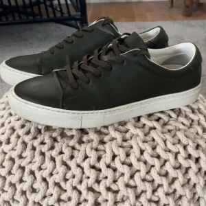 Olivgröna sneakers med vit sula - Snygga olivgröna sneakers med vit sula och bruna snören.