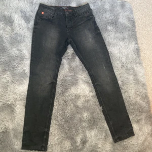 Svarta jeans med slitningar - Ett par riktigt snygga svarta jeans med slitningar i storlek 30/32. Aldrig använda på grund av att dem var för stora. Köpta för 900kr . Tar även emot byten!