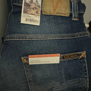 Blå jeans från Nudie Jeans w30L34 - Snygga blå jeans från Nudie Jeans i modellen Thin Finn. Tillverkade av 100% ekologisk bomull med en klassisk femficksdesign och dragkedja. Perfekta för en stilren look med en slim passform.