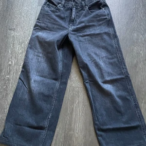 Svarta jeans från Uniqlo - Snygga svarta jeans från Uniqlo med en loose passform. De har en klassisk femficksdesign och är tillverkade i ett robust denimtyg. Perfekta för en avslappnad stil. Som ny! Köpt i Berlin. 