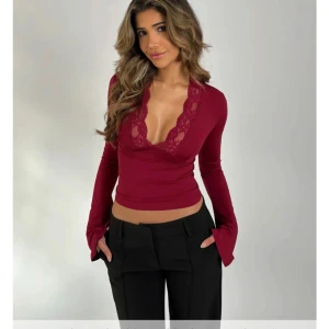 Vinröd topp med spetsdetaljer från Venderby's - Snygg vinröd topp från Venderby's med djup v-ringning och spetsdetaljer. Långärmad design med lätt utsvängda ärmar. Perfekt för en elegant look. Tröjan sitter väldigt smickrande på kroppen och passar perfekt både till fest och till vardags. Den är aldrig använd med alla lappar kvar. Den är just nu slutsåld på hemsidan i den här storleken. 