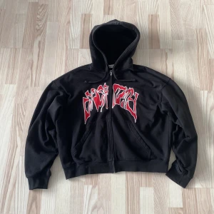 Svart box hoodie från Weekday - Säljer en svart hoodie från Weekday med en cool röd och vit text på framsidan. 