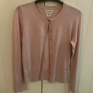 Ljusrosa kofta från Lindex ( Holly & Whyte )  - Helt ny utan prislapp! Superfin ljusrosa färg med eleganta guldfärgade knappar 🌟 Perfekt för en klassisk och chic look!  💌 Skicka DM vid intresse! Fynda nu!