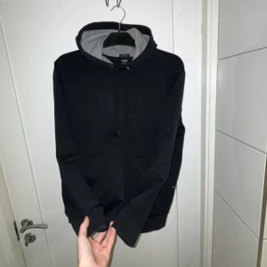 Boss Hoodie Svart - Säljer en stilren svart hoodie från Boss med grå insida i huvan. Passar storlek S och storlek M. Fick i present och använder knappt därför billigt pris. Väldigt bra skick! 