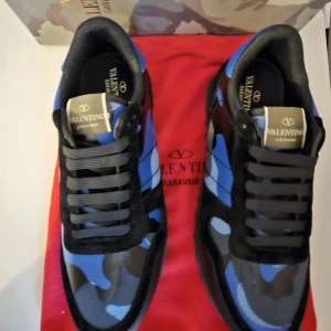 Valentino rockrunners - Snygga Valentino sneakers med ett coolt blått och svart camouflage-mönster. Skorna har snörning och är perfekta för en trendig look. Kommer med originalförpackning och röd dustbag.