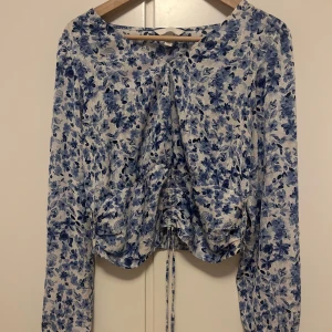 Blommig blus  -  Blommig blus från H&M – storlek M  Superfin långärmad blus från H&M i vitt och blått med blommigt mönster. Luftigt och lätt material, perfekt för både vardag och fest. Har en snygg rynkad detalj med dragsko framtill som kan justeras för att skapa en fin passform.  ✔️ Storlek: M (EUR, US, CA, MX, CN 170/96A) ✔️ Skick: Mycket bra, knappt använd ✔️ Märke: H&M  Skicka ett meddelande vid frågor eller om du vill köpa! 💙