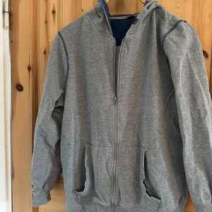 Grå huvtröja från Livergy - Säljer en grå huvtröja från Livergy med dragkedja och långa ärmar. Perfekt för en avslappnad stil. Tröjan har en bekväm passform och är tillverkad i mjukt material.