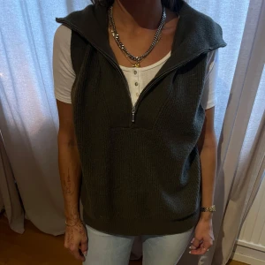Olivgrön stickad väst med dragkedja - Säljer en snygg olivgrön stickad väst med dragkedja framtill. Perfekt för lager-på-lager under höst och vår. Västen har en normal passform och är supermjuk och bekväm. Passar både till vardags och lite mer uppklädda tillfällen. väst föuffig teddy ves
