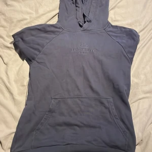 Grå hoodie från Peak Performance - Säljer en snygg och bekväm grå hoodie från Peak Performance. Den har en klassisk design med en känguruficka framtill och en broderad logga på bröstet. Perfekt för både vardag och chill dagar. Passar bra till höst och vinter!