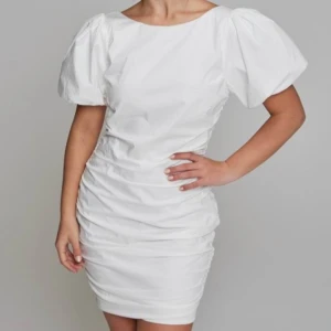 Vit klänning från Nelly  - Säljer en klänning jag beställde inför min konfirmation men som tyvärr var för stor.  Lappen är kvar och köpt för 500kr. Modellen har 34 på bilderna. Klänningen är perfekt inför student, konfirmation eller någon annan typ av festlighet! 