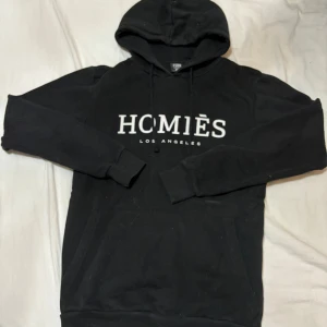 Svart hoodie  - En svart hoodie med ett tryck på där de står homies, hel svart på back sidan
