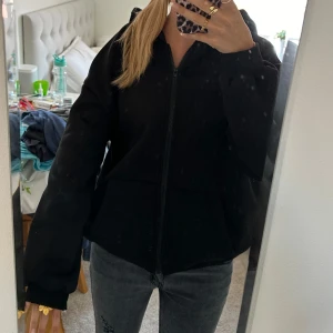 Svart hoodie med dragkedja - Säljer en svart hoodie med dragkedja. Den är superbekväm och perfekt för höst och vinter. Den har en luva och långa ärmar, vilket gör den extra mysig. Passformen är lite oversized, vilket ger en avslappnad look.