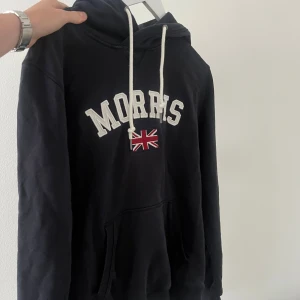 Morris hoddie  - Säljer denna riktigt populära Morris hoodie i bra skick. Den är sparsamt använd. Den är mörkblå och har de populära märket på framsidan. Hoodie har även metal detaljer på snörena där det står morrris på. Vid fler frågor är det bara att höra av sig. 