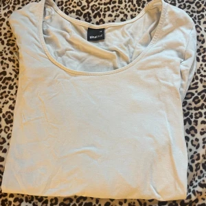 Vit långärmad topp från Gina Tricot - Säljer en enkel och stilren vit långärmad topp från Gina Tricot. Den är gjord i ett mjukt och bekvämt material, perfekt för vardagsbruk. Toppen har en rund halsringning och en tight passform som framhäver figuren. Perfekt att matcha med jeans eller kjol för en avslappnad look.