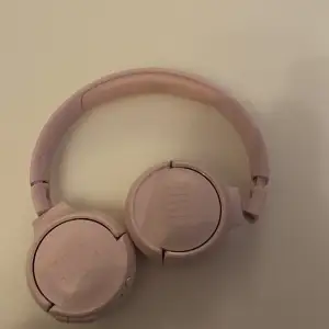 Säljer ett par rosa JBL hörlurar i bra skick. De är bekväma och har en snygg design med vadderade öronkuddar. Perfekt för musikälskare som vill ha stil och komfort. Inkluderar en orange laddningskabel.