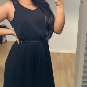 Svart klänning med skärp - Svart klänning med svarta knappar där bak och skärp som ingår med klänningen. Har använts ungefär tre gånger. Storlek S men kan även användas för M. 