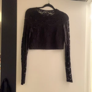 Svart magtröja - En svart magtröja, inte jätte lång tröja. Tröjan är ganska öppen i överdelen men vid magen är den täckt