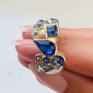 Silverring med blå stenar - Säljer en unik och stilren silverring med flera blå stenar i olika former. Ringen har en stor droppformad blå sten i mitten, omgiven av mindre runda och fyrkantiga stenar. Perfekt för att ge en färgklick till din outfit! Justerbar! Okänt material 