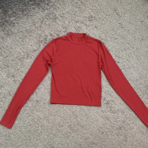 Röd ribbad polotröja från FB Sister - Säljer en snygg röd ribbad polotröja från FB Sister. Perfekt för höst och vinter med sin långa ärmar och sköna passform. Tröjan är i storlek XS och passar perfekt till både vardag och fest. Superfin att matcha med jeans eller kjol!