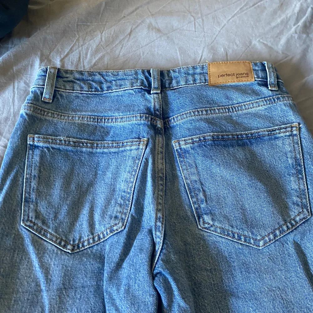 Säljer ett par blå bootcut jeans från ginatricot i storlek 32. De har en snygg slitning på ena benet och klassiska femficksdetaljer. Perfekta för en avslappnad look! Skriv för bilder på eller mått🩷. Jeans & Byxor.