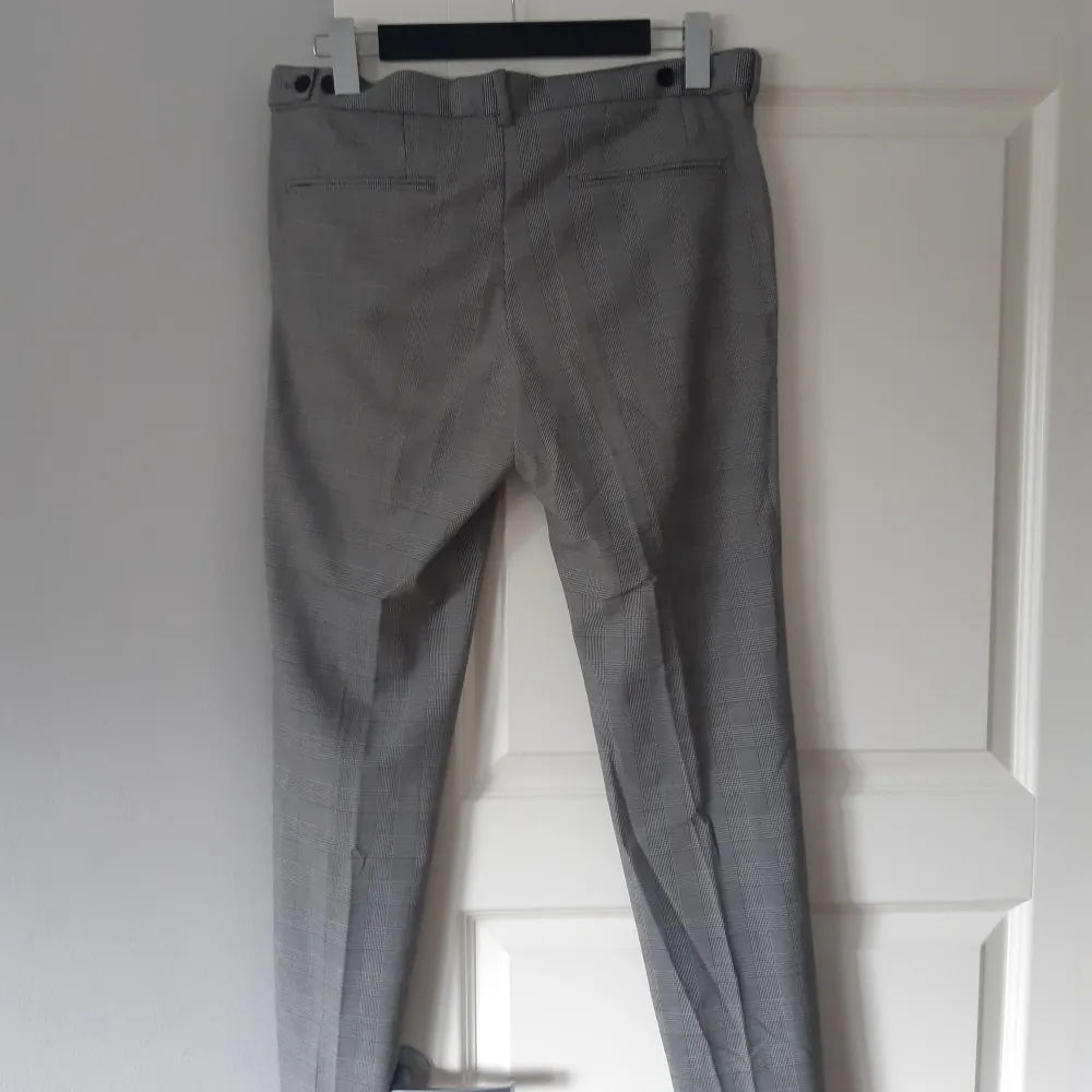 Säljer ett par stiliga grå kostymbyxor från H&M i storlek 32. Byxorna har ett klassiskt rutmönster och en skinny fit som ger en modern look. Perfekta för både kontoret och festligare tillfällen. Endast använda 2-3 gånger och redo för en ny ägare!. Jeans & Byxor.