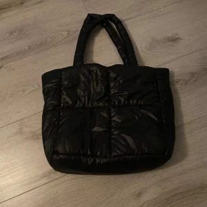 Svart väska - Säljer en snygg svart väska från HM, den har en puffig design med både långa och korta handtag. Väskan är rymlig och jag säljer från min syster.💕
